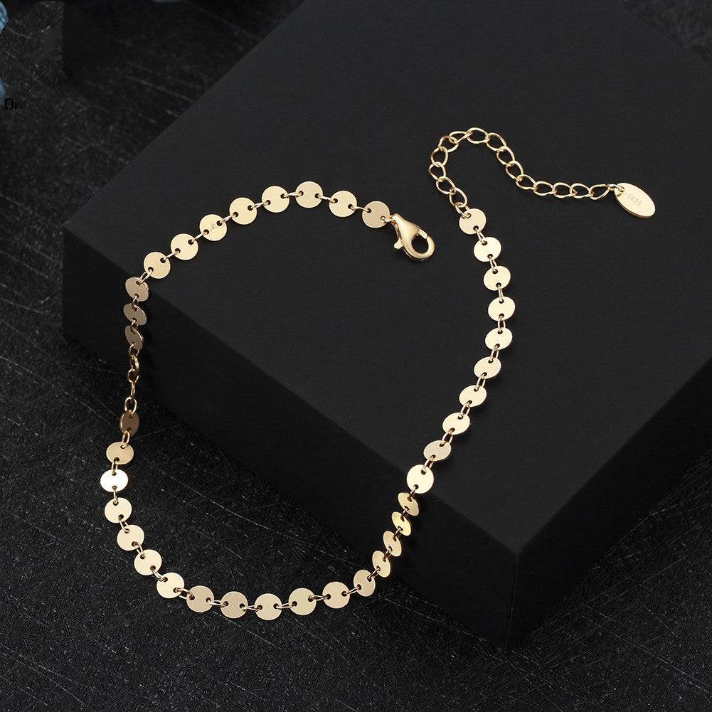 Gold anklet with circular links on black box