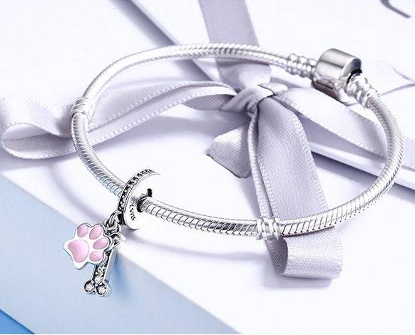 Elegant Pink Bone Charm attached to a silver bracelet, featuring a pink paw and diamanté bone. A perfect accessory for dog lovers.