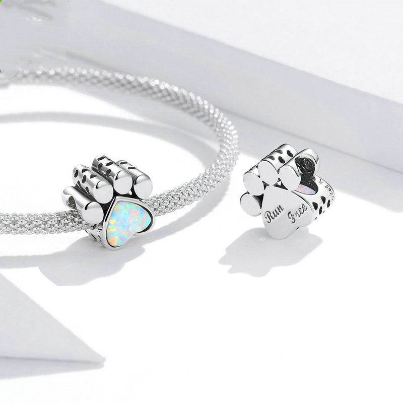 Two dog paw charms with opal hearts on bracelets