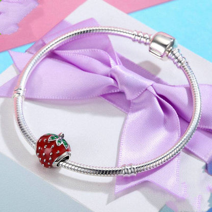 Elegant silver bracelet adorned with a Strawberry Charm, presented on a gift box with a purple ribbon, making it a perfect jewelry gift choice.