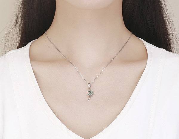 Coconut tree charm necklace worn on a person.