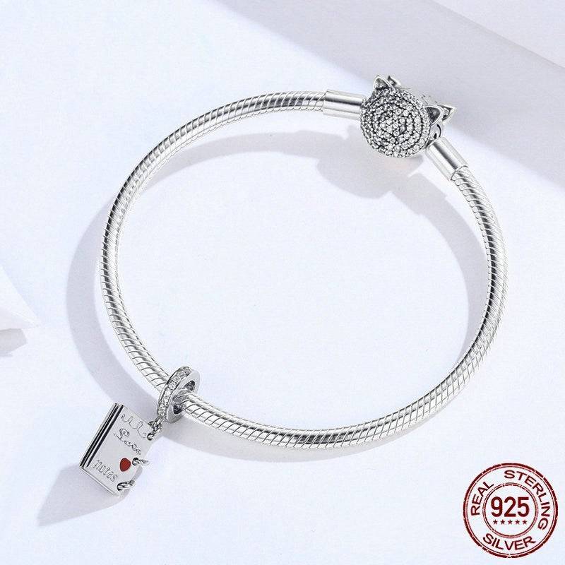 Sterling silver bracelet with love notes charm attached, elegant design.