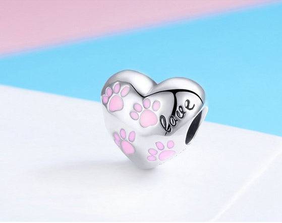 Close-up of Pink Paw Charm with heart shape, pink paw prints, and 'love' engraving. A stylish jewelry piece for pet enthusiasts.