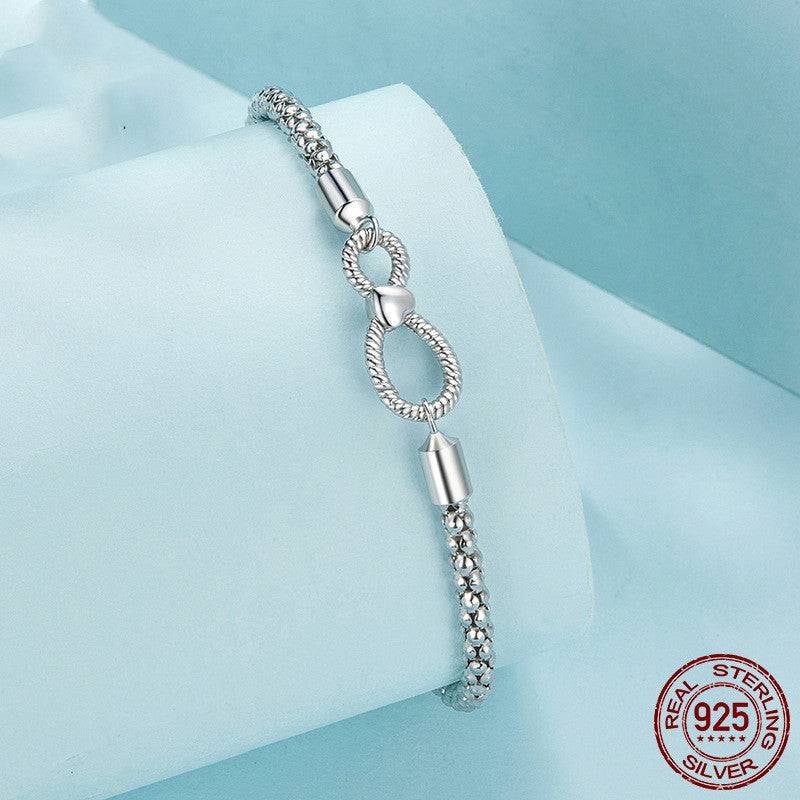 Infinity Knot Silver Bracelet displayed on light blue fabric